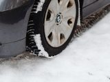 Close-up of a car's tire on a snowy road, highlighting the winter season conditions.