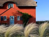 a red house with a thatched roof and a stone wall