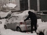 a person shoveling snow off a car