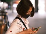a woman wearing a face mask looking at her cell phone