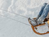 a woman riding a sled down a snow covered slope