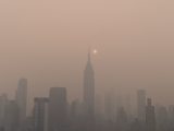 a foggy city skyline with the sun in the distance