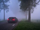 a car driving down a road in the fog