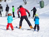 A group enjoying skiing lessons on a snow-covered mountain under clear skies.