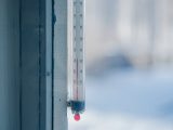 Close-up of an outdoor thermometer against a frosty winter backdrop.