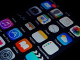 Close-up view of smartphone displaying various apps on the home screen.