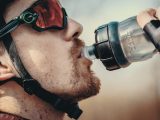 a man wearing a helmet and goggles drinking from a water bottle