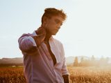 man in white dress shirt standing on brown grass field during daytime