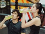 Fit Asian couple hydrating at the gym after an intense workout. Refreshing drink break.