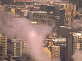 City skyline with smoke rising from buildings, showcasing urban winter scene in Montreal.