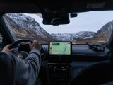 A man driving a car with a gps device in his hand