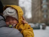 Baby in yellow coat with pacifier in winter