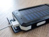 A close-up of a solar charger with a USB connection on a wooden surface, showcasing modern technology.