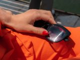 Woman's hand holding sunglasses on orange fabric