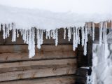 icicles are hanging from the roof of a cabin