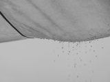 Black and white composition of water drops falling from rag material on gray background