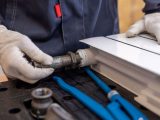 Close-up of a plumber installing a radiator pipe using specialized tools.