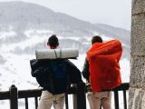 Two male hikers with backpacks enjoying a snowy mountain view in winter.