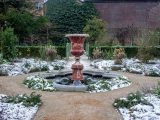 A weathered fountain in a snowy garden