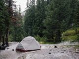 gray tent beside lake surrounded by trees