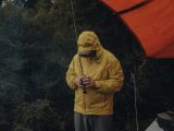 a man in a yellow jacket standing next to a tent