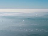 Drone view of modern city covered with thick smog and mist under bright blue sky