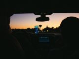 Interior view of a car with navigation app at sunset, highlighting travel and technology.