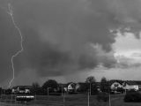 Monochrome image capturing a dramatic lightning strike during a thunderstorm over a neighborhood.