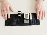 Close-up of hands holding a diabetic glucometer kit on a white table for blood sugar testing.