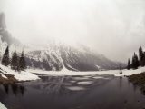 Breathtaking snowy mountain landscape with a frozen lake under a misty sky, ideal for winter and nature themes.