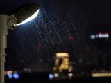 Rain falls in front of a streetlight at night.