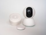 Modern minimalist smart home devices including security camera and sensors in white.