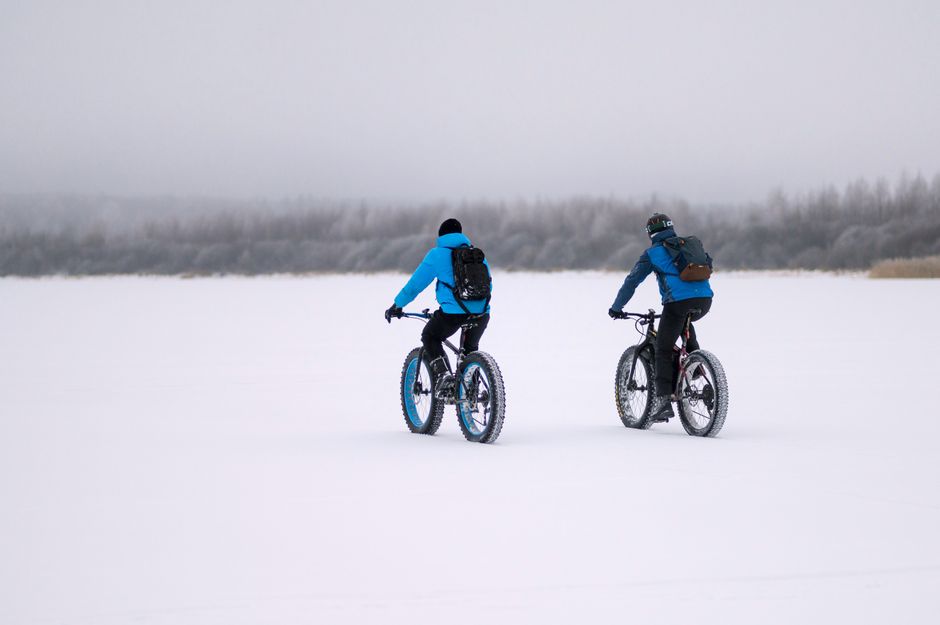 Two cyclists riding fat bikes through a snowy landscape, embracing winter sports and adventure.