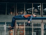 a man laying on a blue bench in front of a building