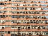 Close-up of an urban apartment building facade with multiple windows and air conditioning units.
