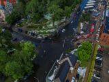 Aerial view of a flooded city intersection surrounded by greenery and buildings after a hailstorm with fire trucks responding.