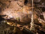 Explore a stunning cave with impressive stalactites and stalagmites in natural lighting.