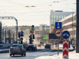 City street with cars, snow, and multiple traffic signs