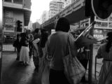 A black and white photo of people waiting at an intersection in Hong Kong.