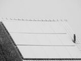 Snow-covered solar panels on a rooftop in winter, highlighting renewable energy challenges in cold climates.