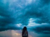 person wearing black and white stripe shirt across blue clouds