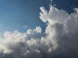 A captivating sky filled with cumulus clouds against a bright blue backdrop, showcasing dynamic weather patterns.