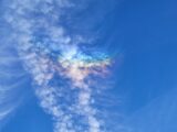 Capture of iridescent clouds showcasing beautiful colors in a clear blue sky.
