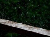 a wooden bench with rain falling down on it