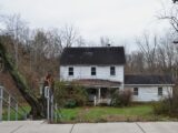 An abandoned white house surrounded by trees