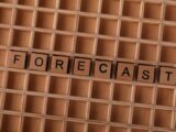 Scrabble-like wooden blocks spelling the word 'forecast' on a wooden grid surface.