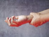 Close-up of hands, one grasping the other, symbolizing pain or discomfort.