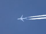 A high-flying Qatar Airways jet leaves contrails in a clear blue sky, showcasing aviation dynamics.