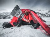 Man shoveling snow outside a tent in the snowy mountains of Gulmarg. Winter camping adventure.