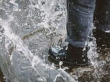 A close-up of a person stomping in water with waterproof boots, capturing a playful splash.